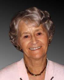 An Older Woman Wearing A Pink Jacket And Beaded Necklace Smiles At The