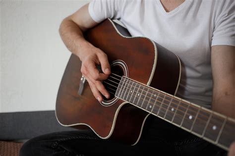 Premium Photo A Man In A White Tshirt Playing Guitar At Homexa