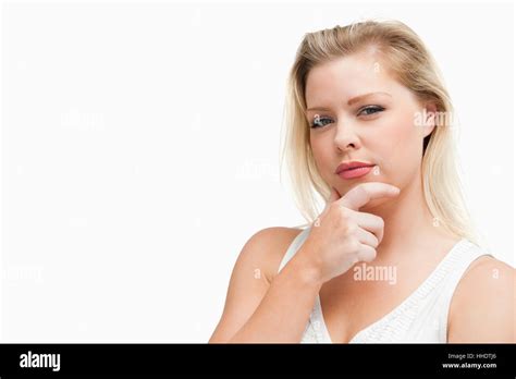 Serious Blonde Woman Placing Her Hand On Her Chin Against A White