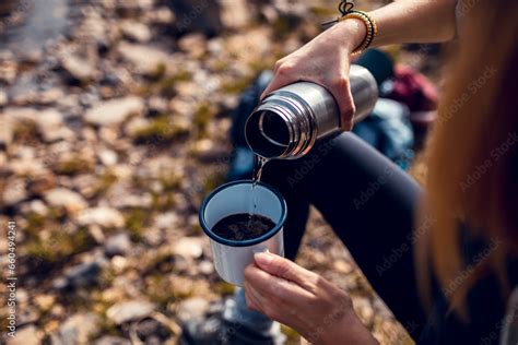 Close Up Of A Young Woman Pouring Warm Water From A Thermos Into A Mug