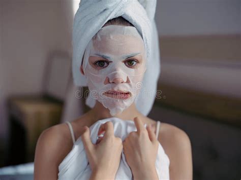 Young Woman Lying On Bed With Moisturizing Beauty Face Mask And White Towel On Her Head After