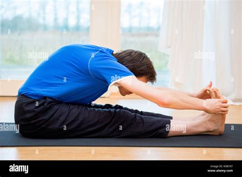 Man Practicing Yoga Indoors In A Retreat Space Doing Seated Forward