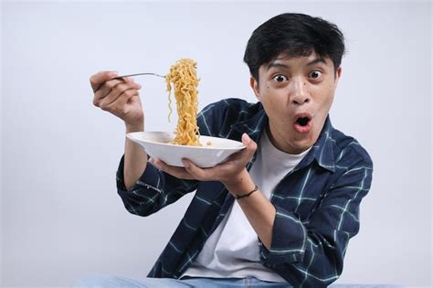 Premium Photo Excited Young Man Eating Noodles With Shocked Expression