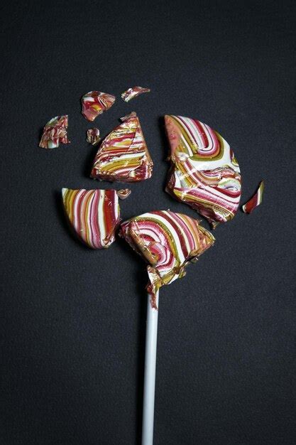 Premium Photo Close Up Of Broken Lollipop Over Black Background