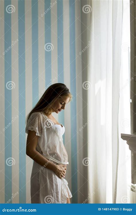 Pretty Young Pregnant Woman Standing By The Blue Stripped Wall In The