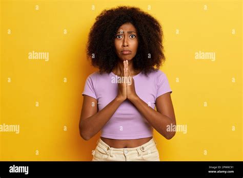 Cute Hopeful Dark Haired Female Model Keeps Palms Pressed Together Under Chin Prays For Good