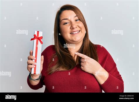Beautiful Brunette Plus Size Woman Holding Gift Smiling Happy Pointing With Hand And Finger