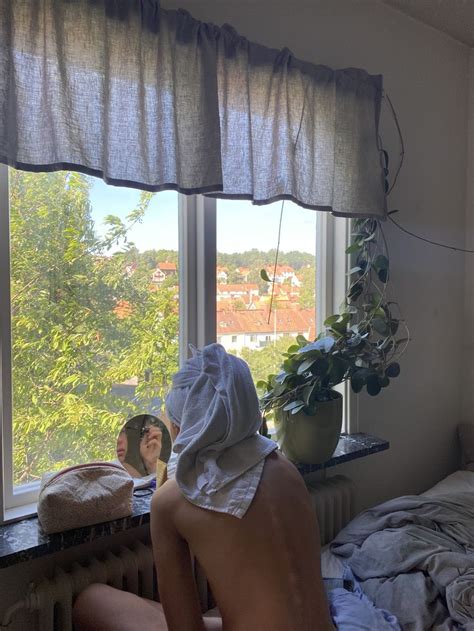 A Naked Man Sitting In Front Of A Window Next To A Potted Plant On Top