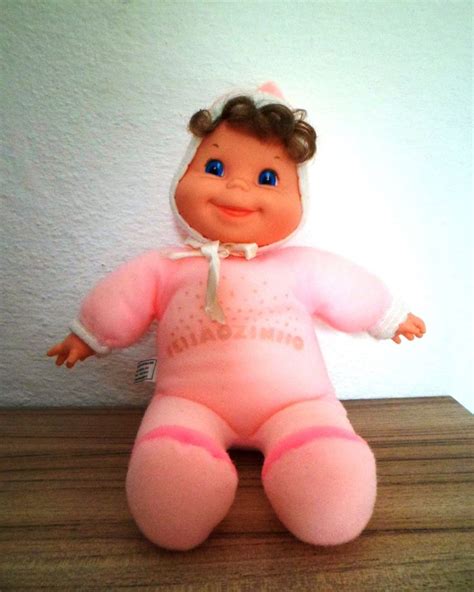 A Pink Doll Sitting On Top Of A Wooden Table Next To A White Wall And