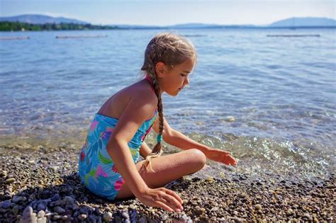 Dziewczyna bawi się i bawi się kamieniami na kamienistej plaży nad