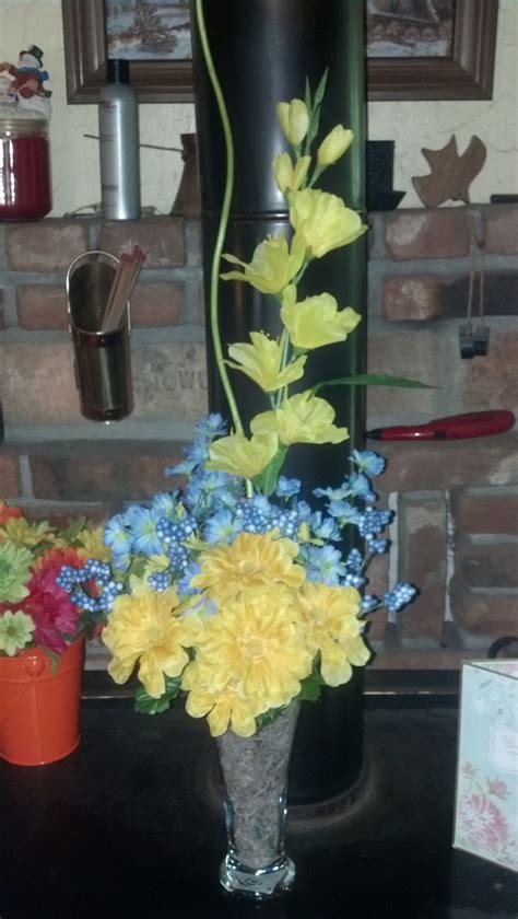 A Vase Filled With Yellow And Blue Flowers On Top Of A Table Next To A