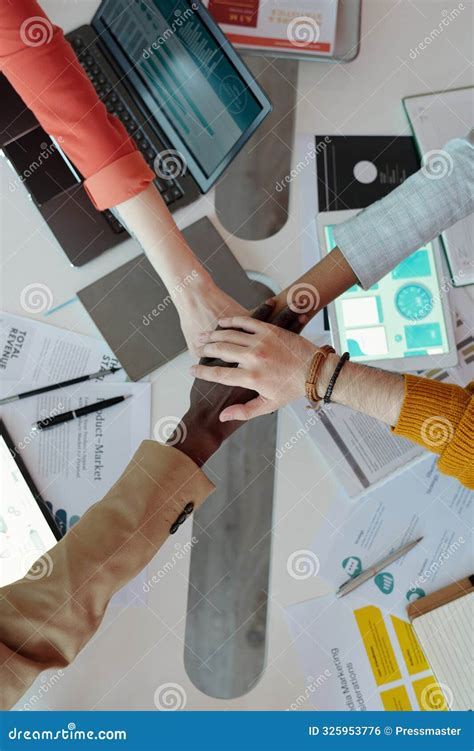 Diverse Hands Joined Over Desk In Office Environment Stock Photo