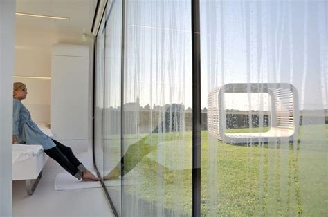 A Woman Sitting On Top Of A White Bench In Front Of A Glass Wall And