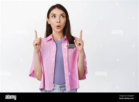 Surprised Brunette Girl Pointing Fingers Up Looking Interested At Shop Advertisement Showing