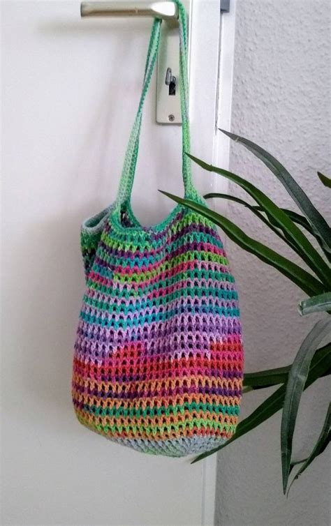 A Crocheted Bag Hanging On A Hook Next To A Potted Green Plant