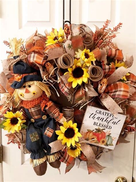 A Scarecrow Wreath With Sunflowers And Fall Decorations Hanging On The