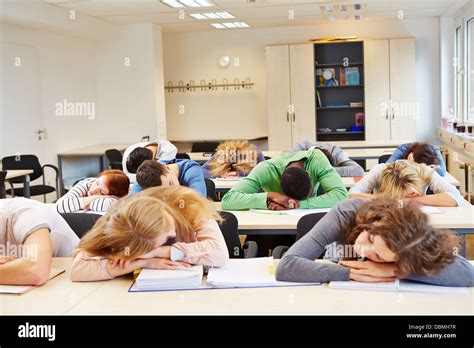 Many Tired Students Sleeping In Classroom With Their Heads On The Stock