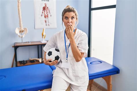 Young Woman Working At Football Therapy Clinic Covering Mouth With Hand