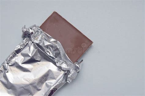 Chocolate Bar Tablet Wrapped In Aluminum Foil Over Gray Neutral