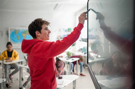 College student explaining some ideas on a touch TV in classroom. Stock Photo | Adobe Stock