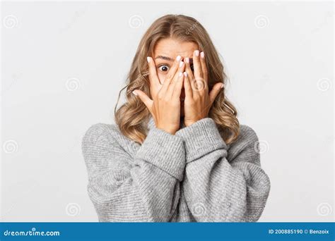 Close Up Of Shocked Or Embarrassed Blond Girl Cover Eyes And Peeking Through Fingers Standing