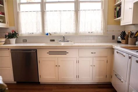 A Kitchen With White Cabinets And Stainless Steel Dishwasher In The