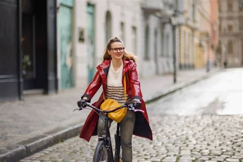 Stylish Woman In Red Rain Coat Outside On The City Street Riding