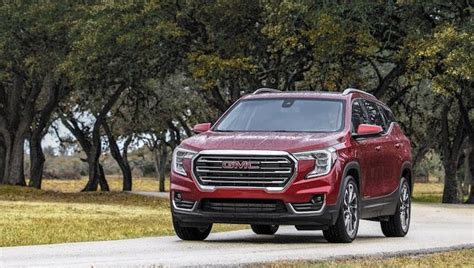 The New Gmc Acura Suv Is Driving Down A Tree Lined Road