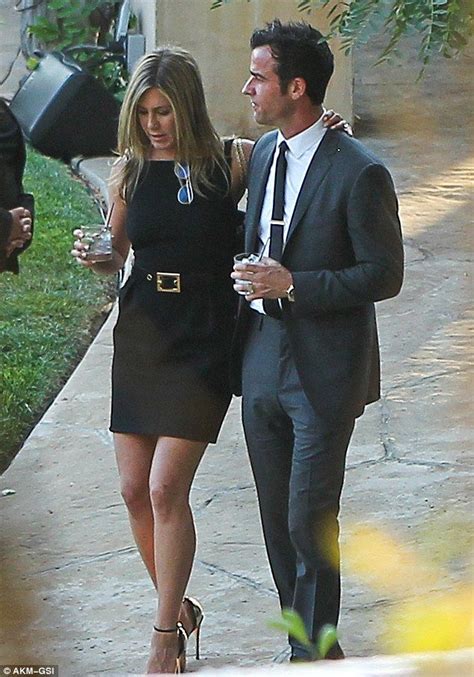 A Man And Woman Walking Down A Sidewalk With Drinks In Their Hands One