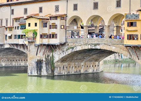 Tourists On The Ponte Vecchio Bridge Over Arno River In Florence