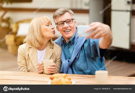 Mature Woman Kissing Her Husband While He Taking Selfie Near Motorhome