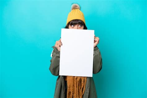 Jovem Mulher Latina Vestindo Jaqueta De Inverno Isolada Em Fundo Azul Segurando Um Cartaz Vazio