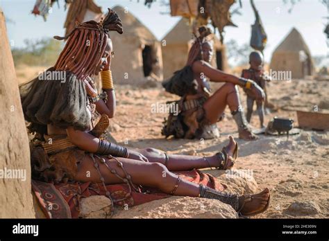 Himba Women Sitting Outside Their Huts In A Traditional Himba Village