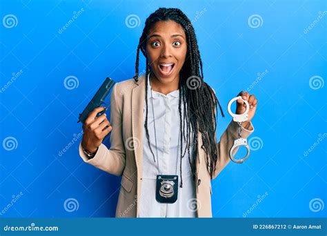 African American Police Woman Holding Gun And Handcuffs Celebrating