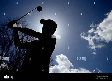 silhouette of young golfer holding a golf club driver about to swing to ...