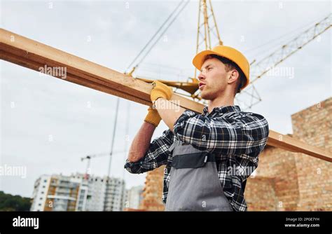 Transporting Wooden Boards Construction Worker In Uniform And Safety