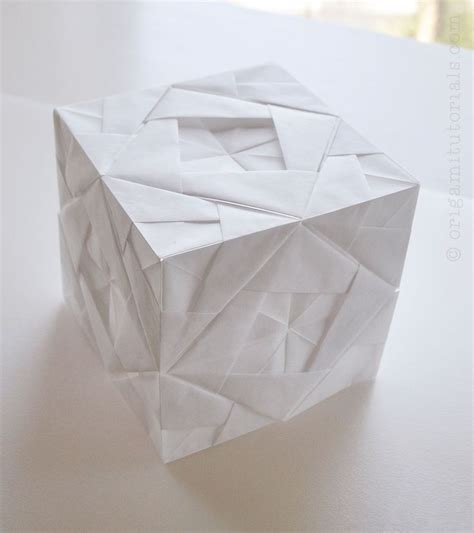 An Origami Cube Sitting On Top Of A White Table Next To A Window