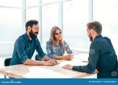 Group Of Successful Young People Sitting At The Negotiating Table