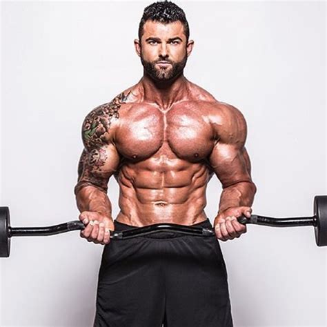 A Man Holding Two Barbells In Front Of His Face And Chest While