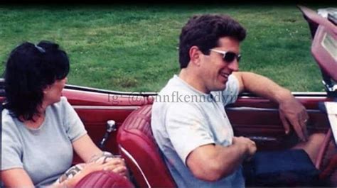 A Man And Woman Sitting In The Back Of A Red Convertible Car With Open Doors