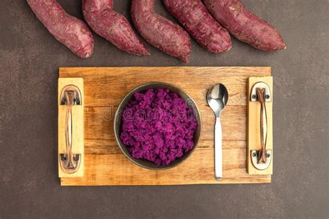 Purple Yams Pile And Mashed Purple Sweet Potatoes On A Dish And Spoon On A Wooden Tray Placed On