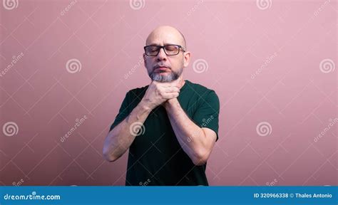 Bearded Bald Man With Prescription Glasses Squeezing His Neck With Both