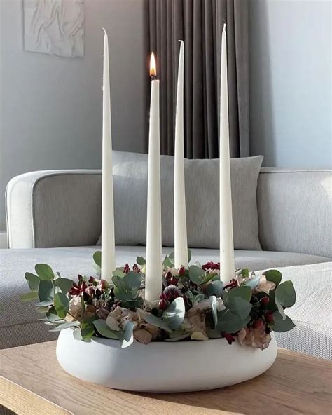 Candles Are Arranged In A White Bowl With Greenery And Flowers On The