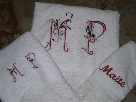 Three White Towels With Embroidered Letters On Them