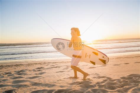 日落时男孩在海滩上携带冲浪板的全景视图高清图片下载 正版图片501862503 摄图网