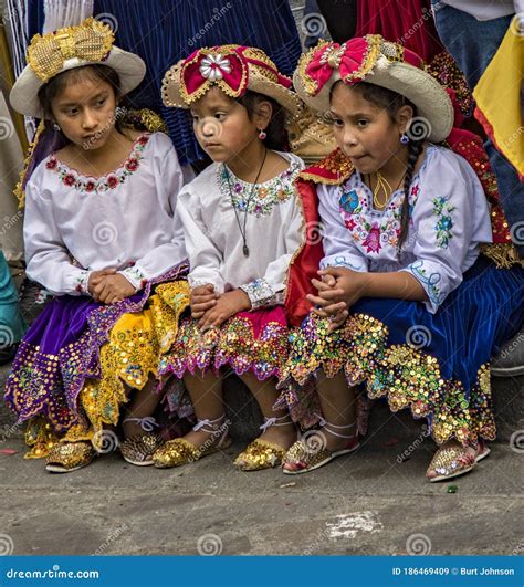 Three Girls In Traditional Ecuadorian Clothes Sit On Street Curb