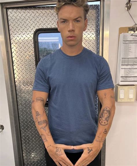 A Man With Tattoos On His Arms Standing In Front Of A Door And Looking