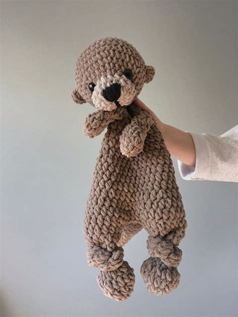 A Hand Holding A Brown Teddy Bear Made Out Of Knitted Yarn With Black Eyes