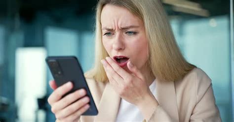 Close Up Shocked Young Businesswoman Read Bad News On Smartphone While Sitting At Workplace