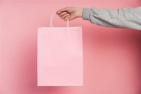 Mano Femenina Sosteniendo Una Bolsa De Papel Rosa Aislada Foto Premium